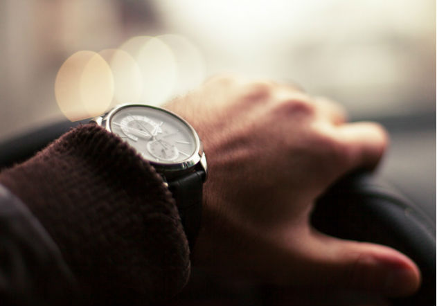 Mano sosteniendo timón de carro con reloj de lujo